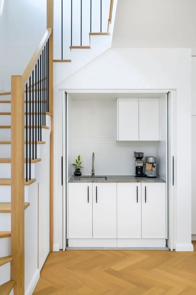 Compact white kitchenette under stairs